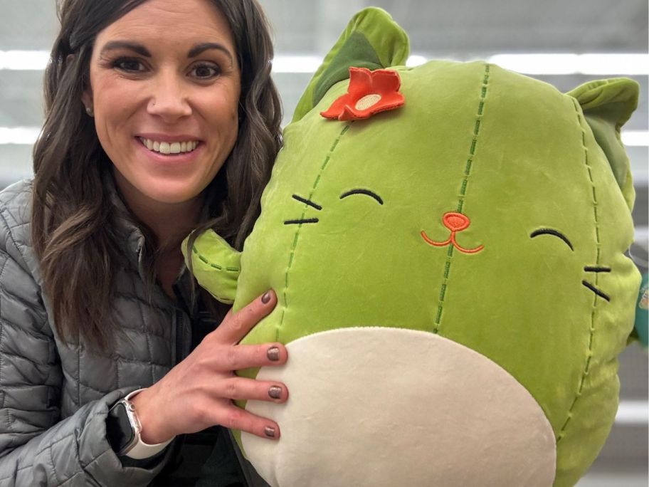 A woman holding a green Squishmallow