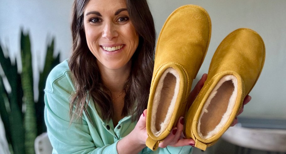 Woman holding mustard color bearpaw boots