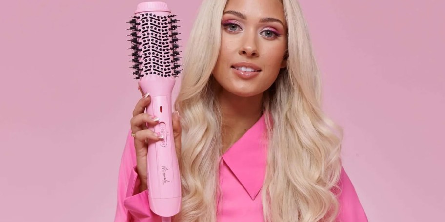 woman holding pink blow dryer brush