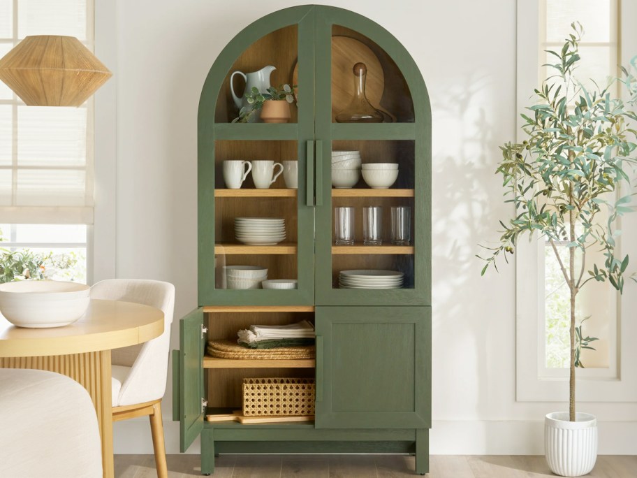 dark green arch cabinet in kitchen full of dinnerware