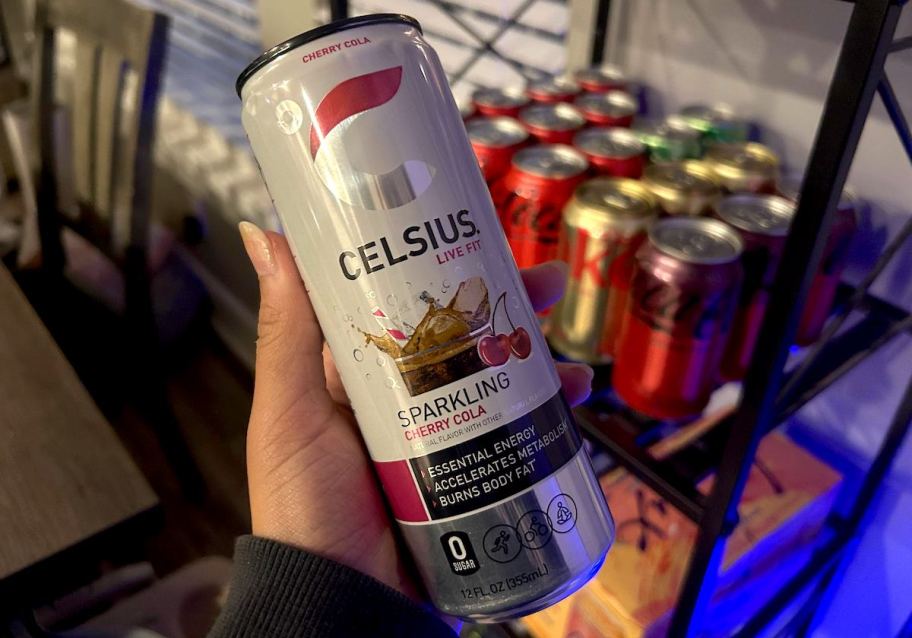 hand holding a celcius cherry cola flavored energy drink