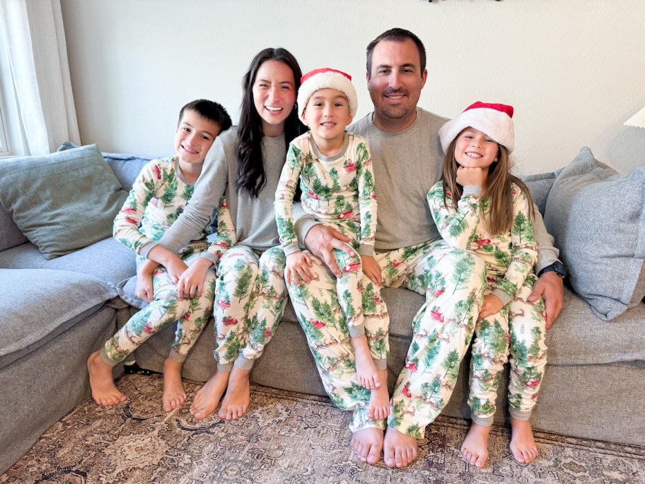 family sitting on couch wearing matching tree christmas pajamas