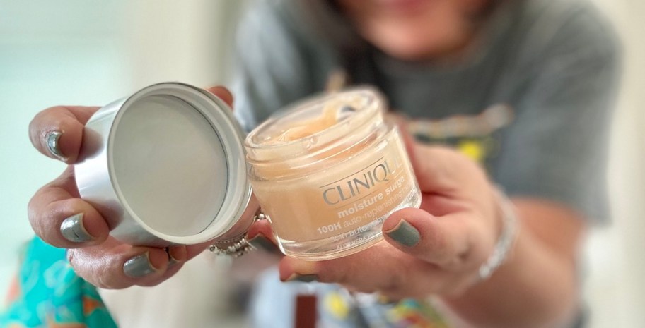 woman holding clinique moisture surge product with lid off