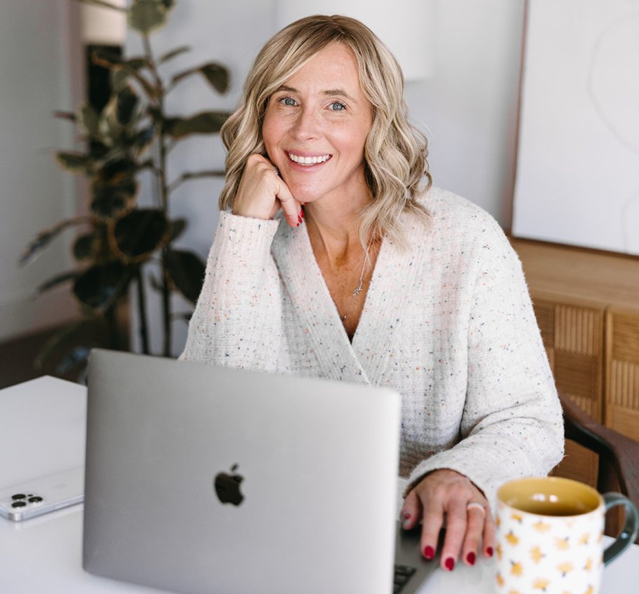 woman resting head on hand sitting at table with apple laptop