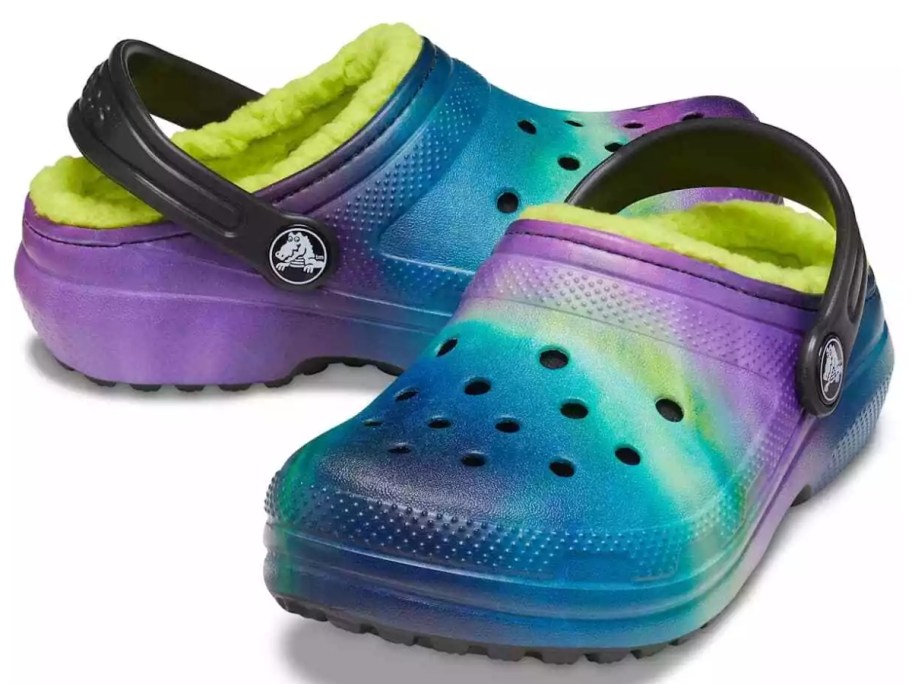 a pair of kids crocs in a multicolor pattern with purples, blues, greens, and yellows