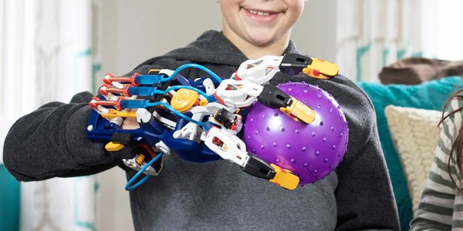 kid wearing cyborg hand holding ball 