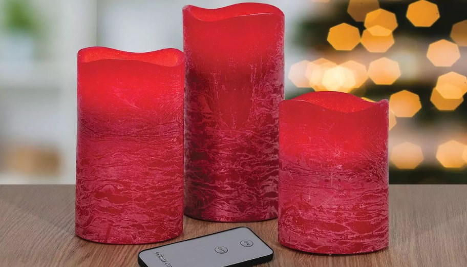 3 red candles on table with remote