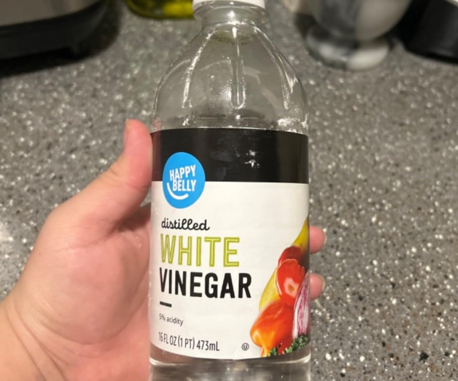 holding a bottle of white vinegar