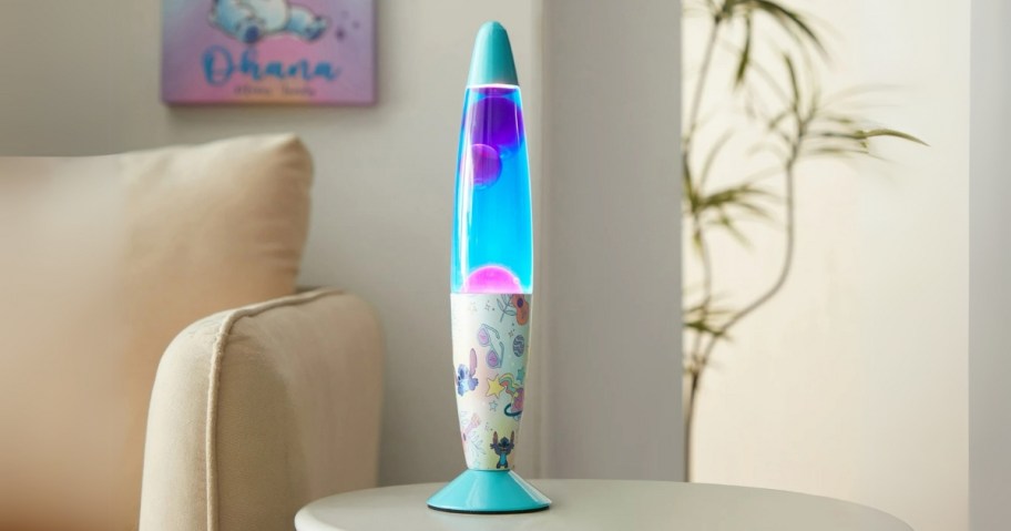 a blue, pink, purple, and white Lava lamp on a table - it has Disney's Stitch on the base of it