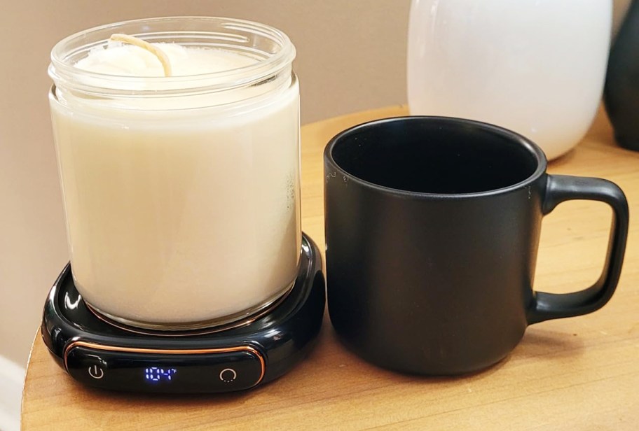 candle sitting on warmer next to mug