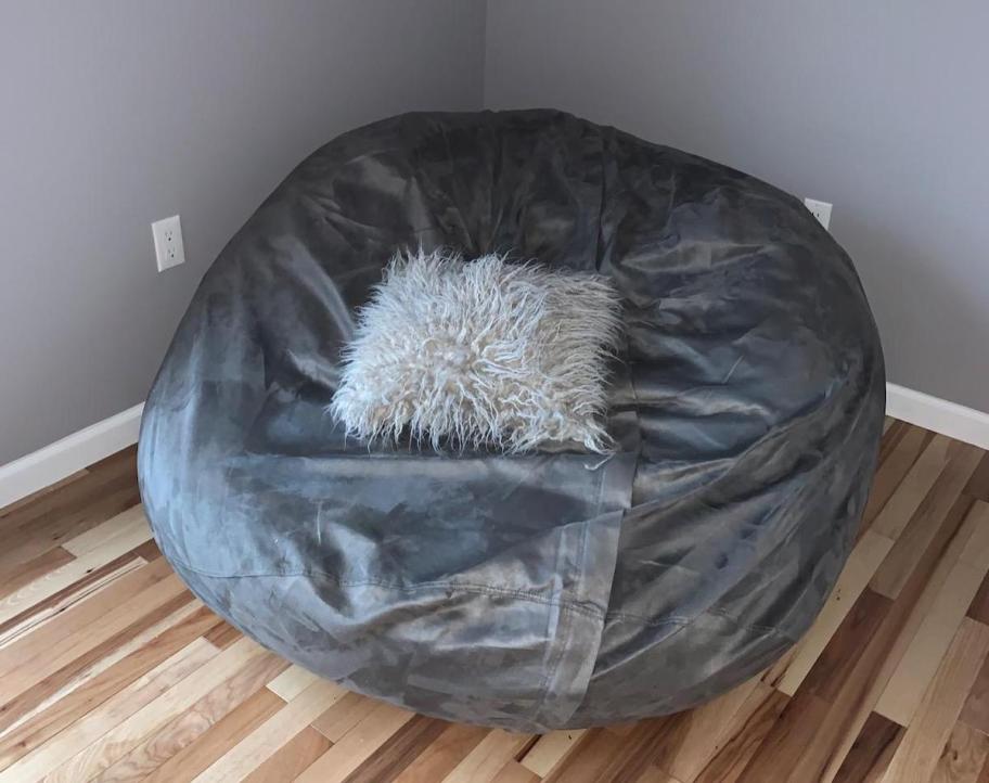 Gray microsuede beanbag chair in corner of room with bow for a pillow 