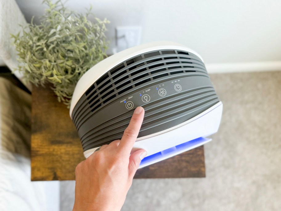 hand reaching for air purifier on table 