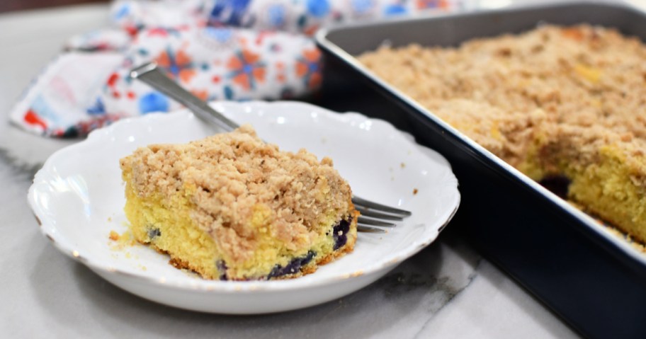 slice of blueberry crumb cake next to pan