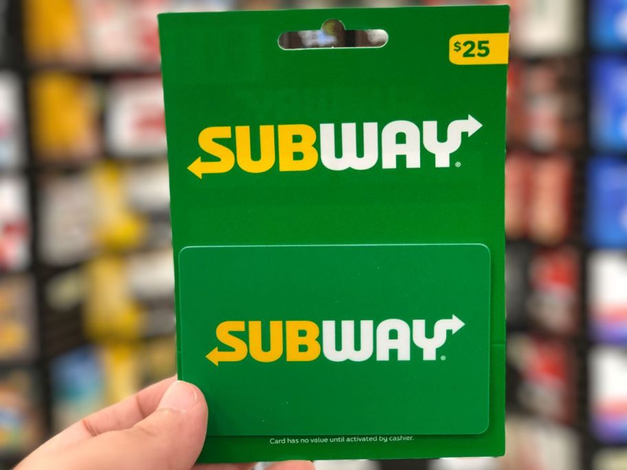 a mans hand holding a $25 subway gift card