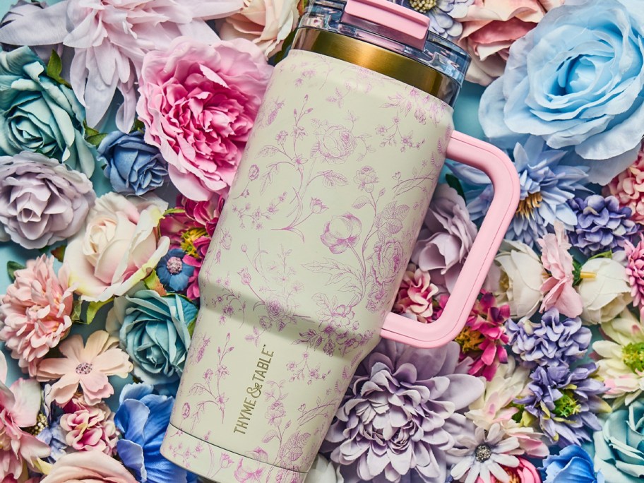 white and pink floral tumbler laying on flowers