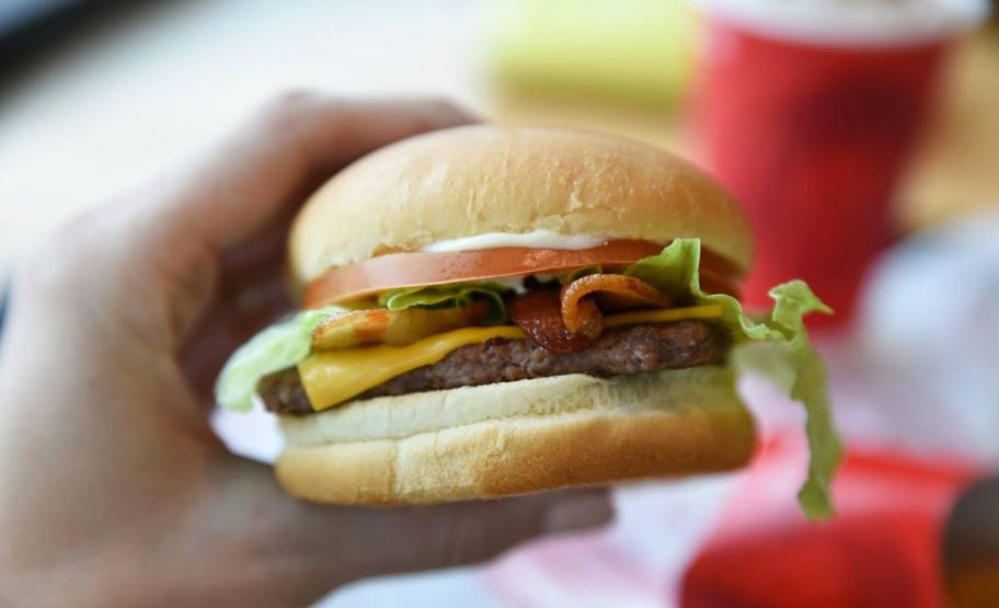 a hand holding a wendys jr bacon cheeseburger