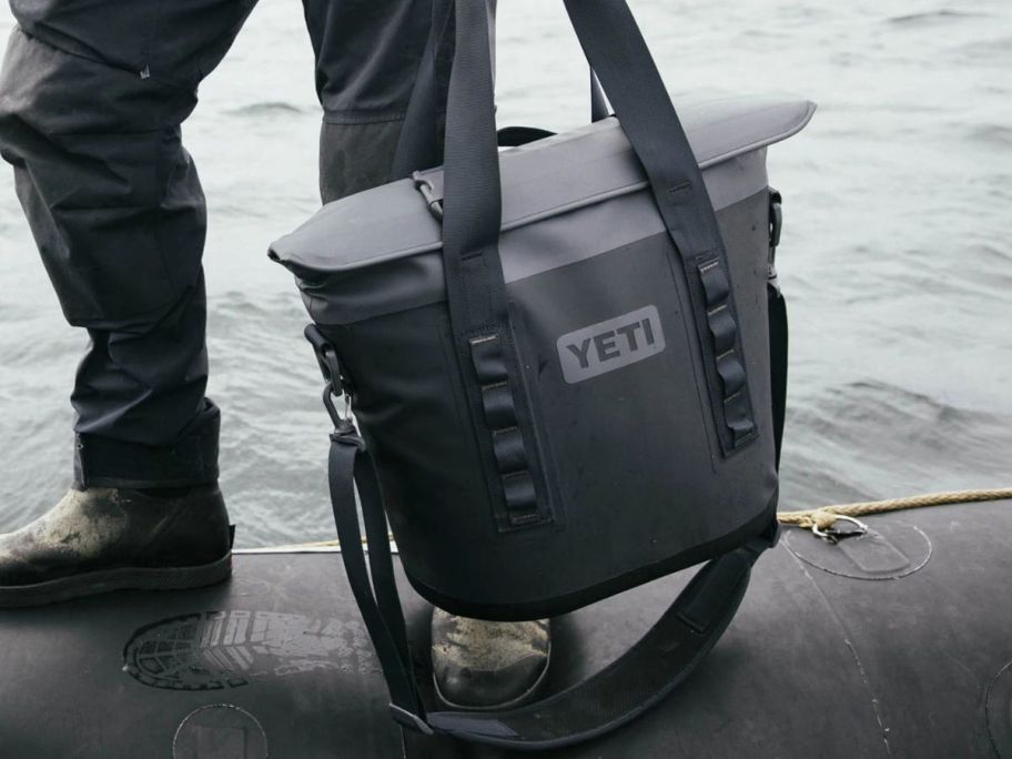 grey YETI Hopper M15 Soft Cooler in hand on beach