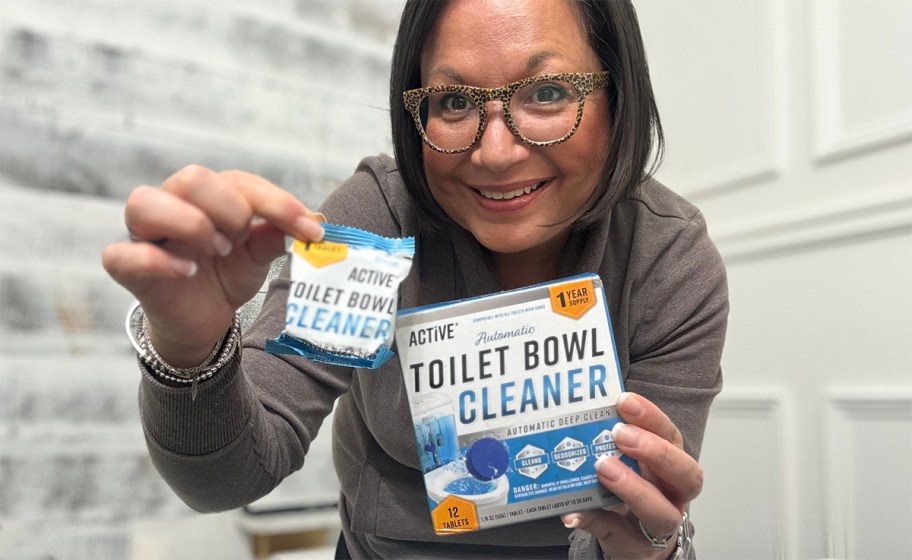 Woman standing in bathroom holding box of ACTIVE toilet bowl cleaner