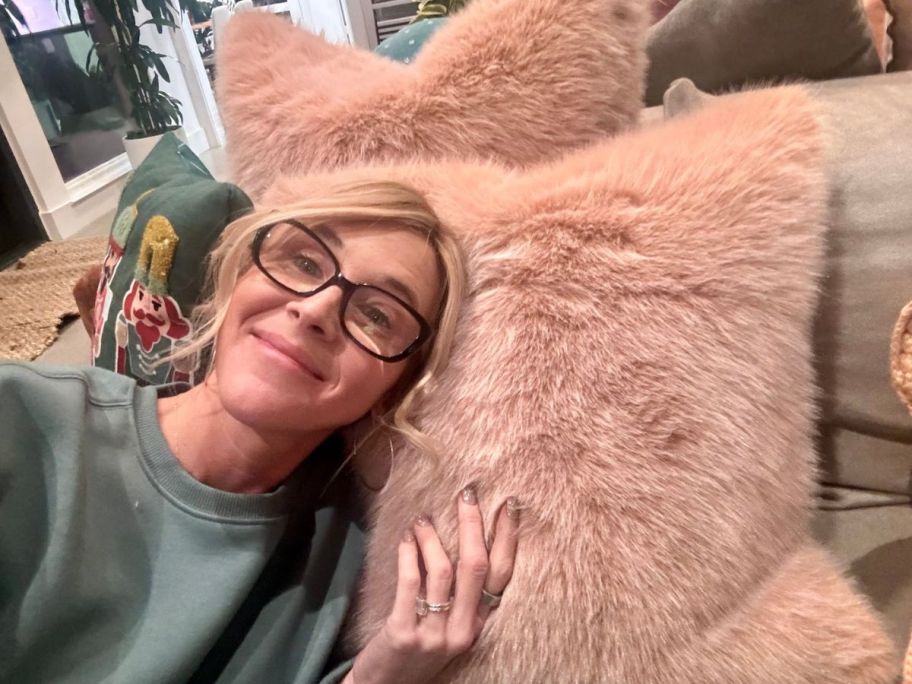 A woman lounging on a pink Anthropologie Pillow