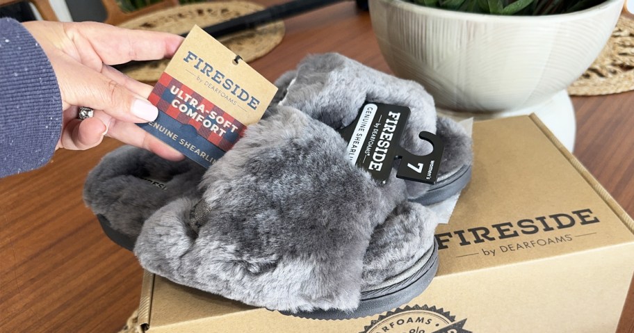 grey pair of dearfoams slippers on top of a shoe box