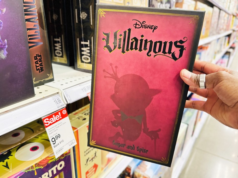 hand holding Disney Ravensburger Villainous Sugar and Spite Game in front of store shelf