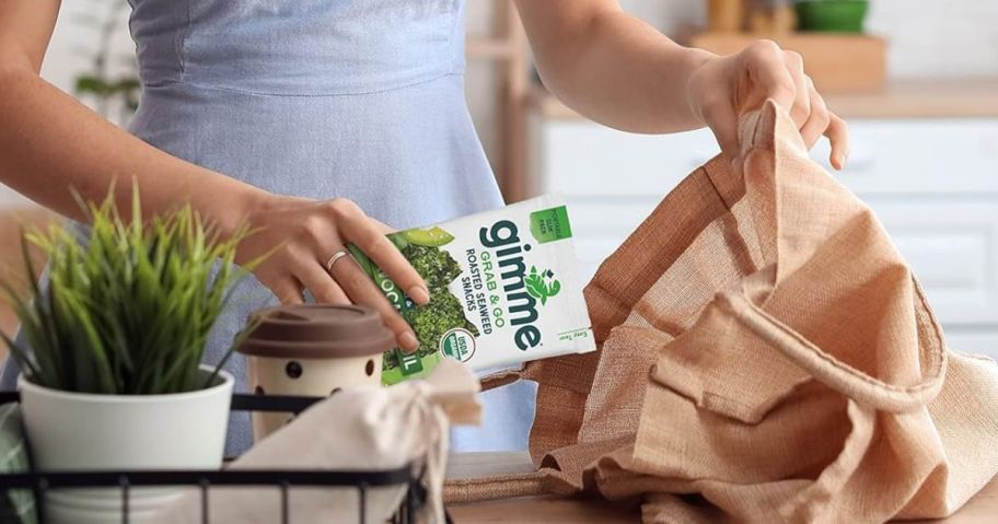 Woman placing a Grab & Go Pack of gimMe Seaweed snacks in a bag