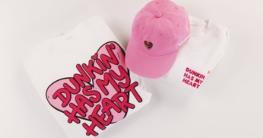 a folded up white shirt with the words "Dunkin' has my heart" in red and pink, a pink hat with a brown heart on it and a sticker that says "Dunkin' has my heart"