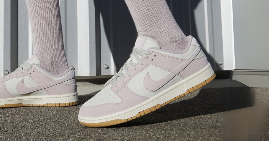 a woman's feet wearing white and light purple Nike Dunks sneakers and light purple socks