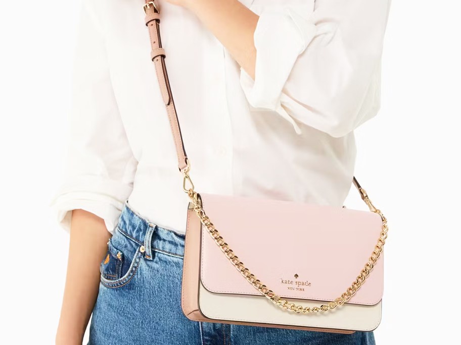 woman in a white top and jeans with a light pink and white crossbody bag