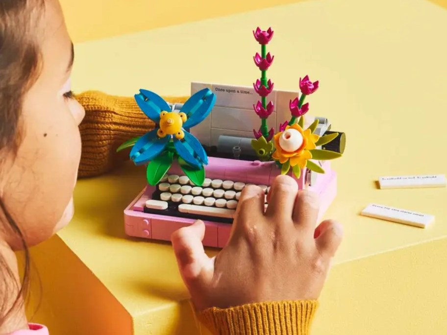 a girl playing with a LEGO pink typewriter set with LEGO flowers