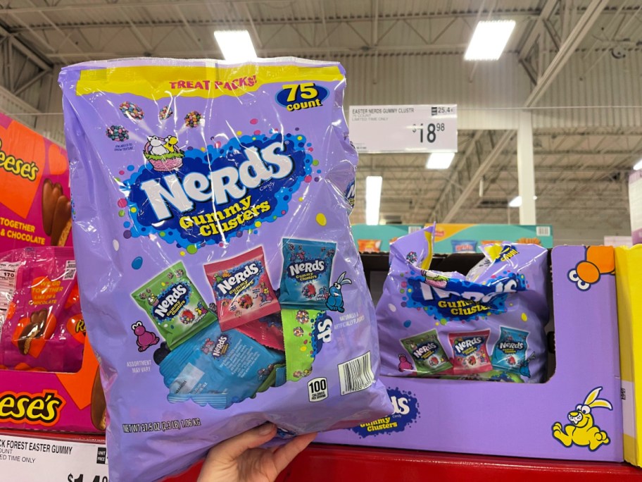 Person holding up purple bag of nerds, Easter themed gummy clusters inside Sam's Club