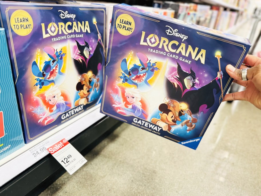 hand grabbing Ravensburger Disney Lorcana Gateway Trading Card Game from shelf