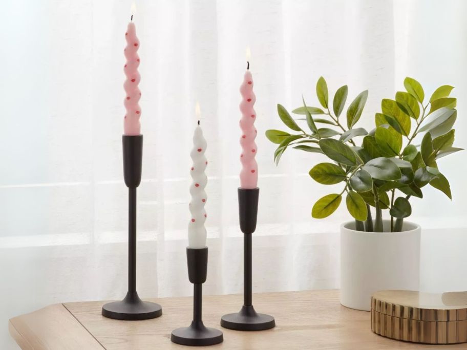 Room Essentials Taper Candle 6-Pack in White & Pink in candle holders on table