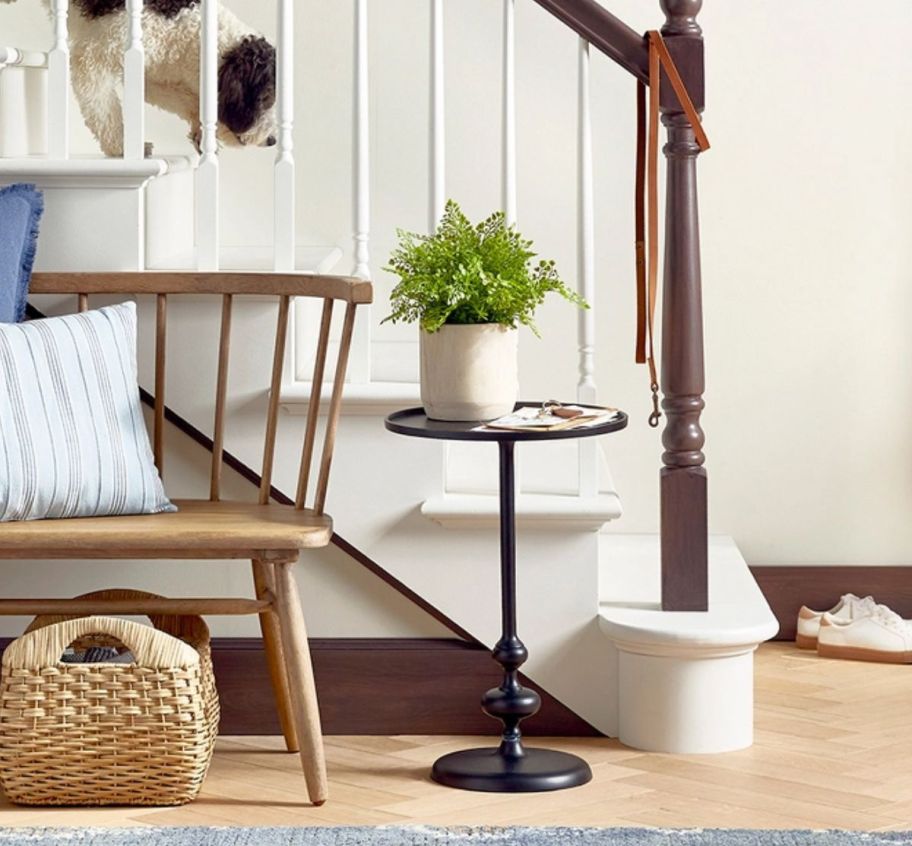 a black turned pedestal table in front of a staircase