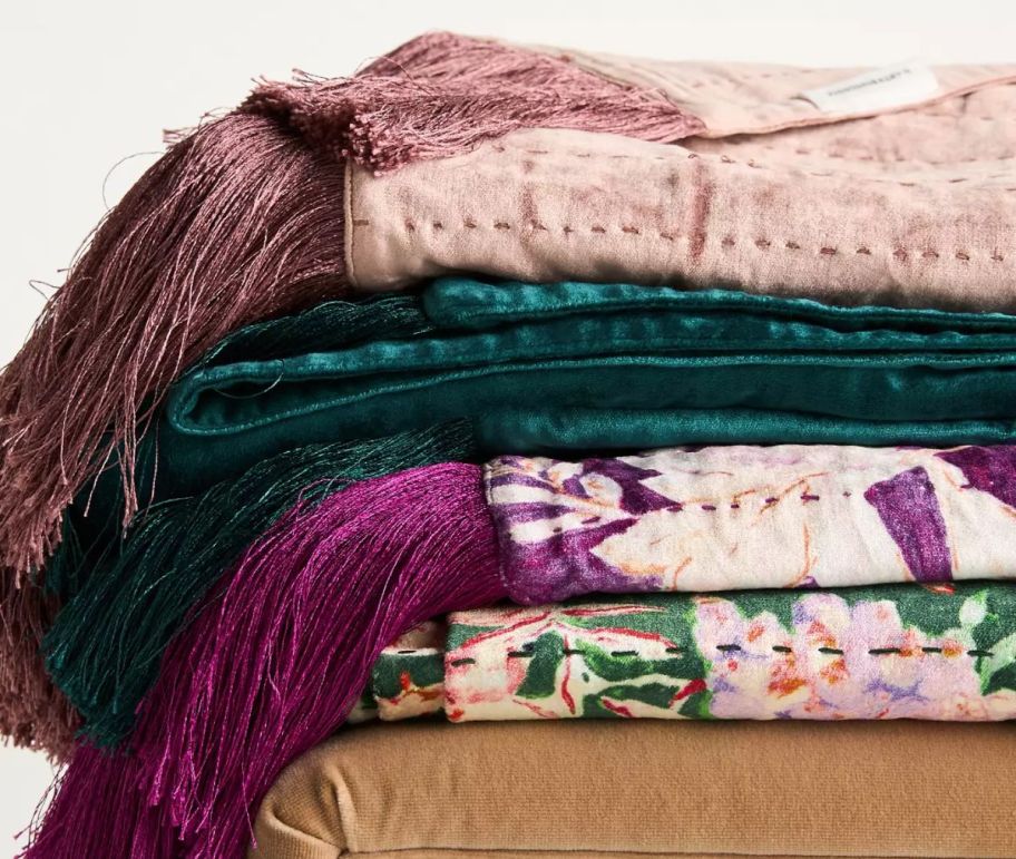 a stack of 4 velvet throw in various colors