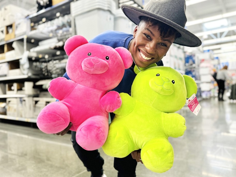 woman holding up pink and green gummy bear plushies in store