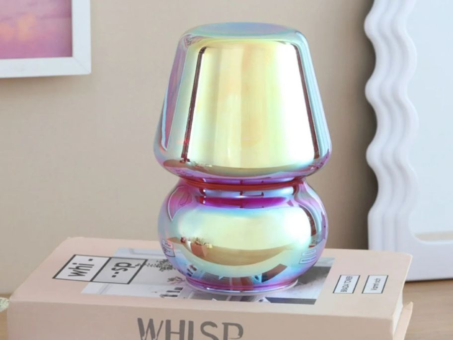 Urban Shop Iridescent 5" x 7.5" Glass Mushroom Lamp on a book