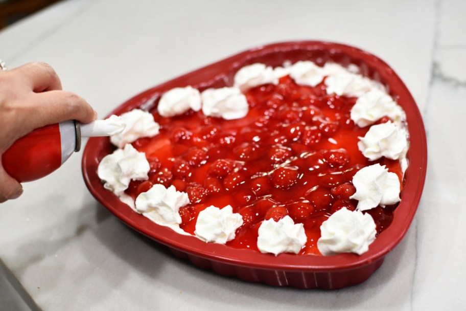 adding whipped cream to cherry delight dessert