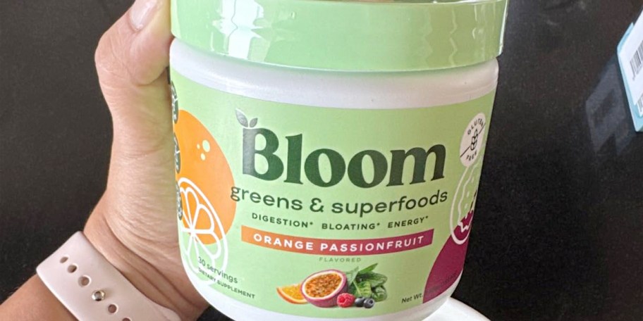 hand holding bloom greens jar 