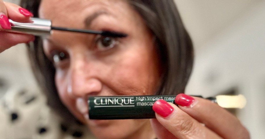 woman holding up a tube of Clinique Mascara and putting it one one her upper eyelashes