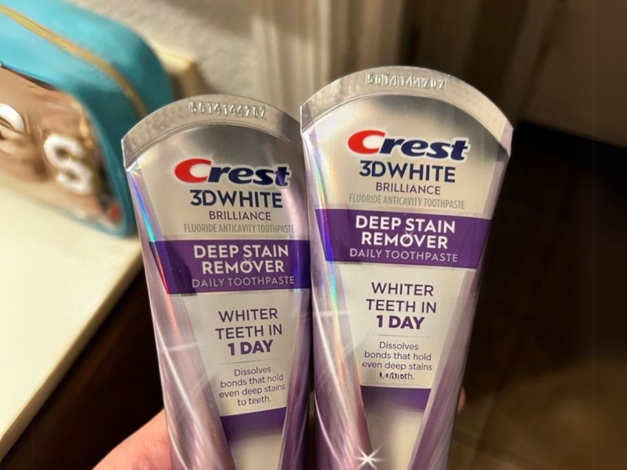 hand holding Crest 3D White Brilliance Deep Stain Remover Brilliant White Toothpaste 3.1oz 2-Pack in bathroom