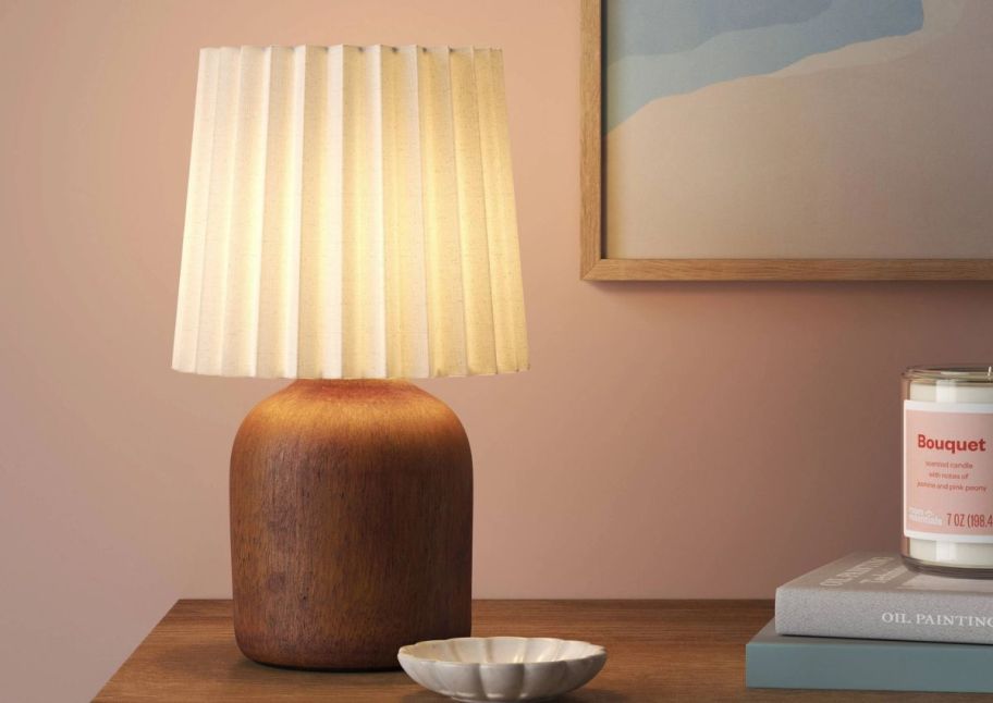 Faux wood mini lamp on a tabletop next to a jar candle