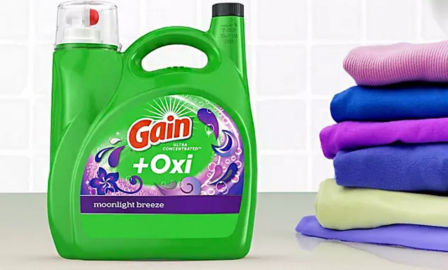 gain laundry detergent bottle sitting on table with towels stacked 