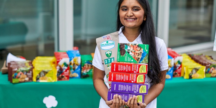 girl holding boxes of girl scout cookies 