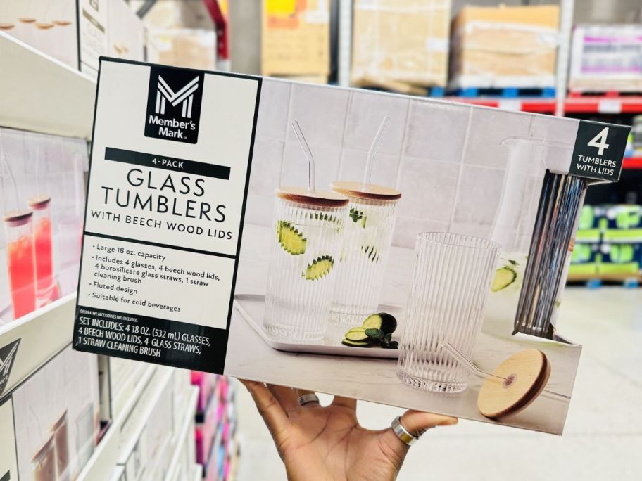 a womans hand holding a box of glass tumblers with lids