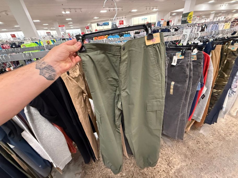 hand holding green girls pants in store