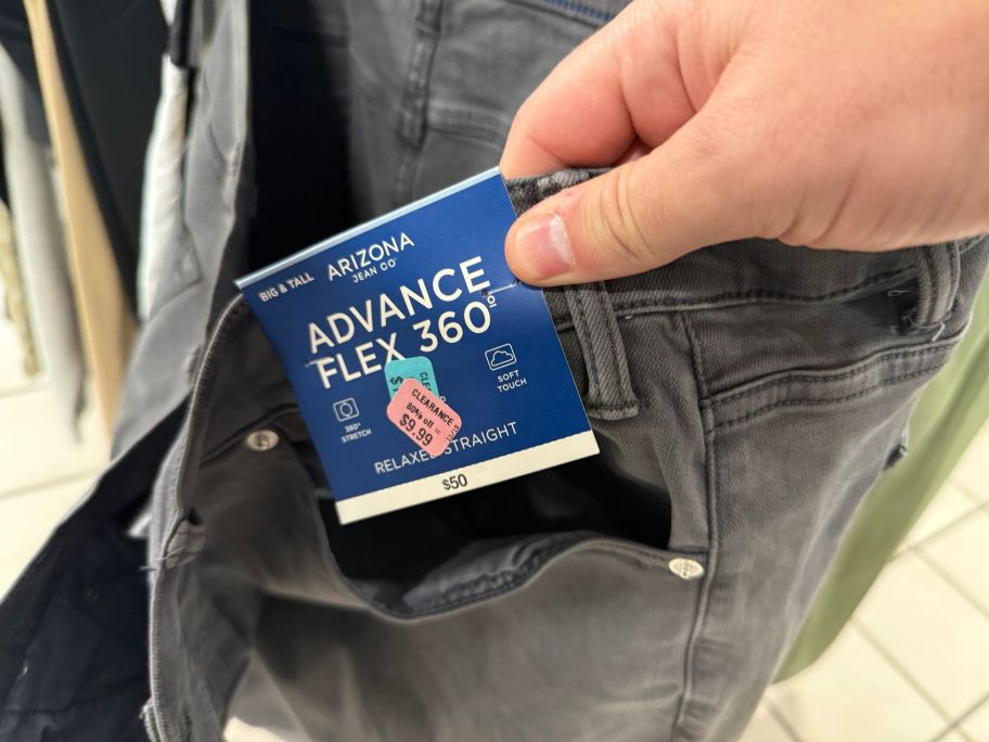 hand holding a tag on men's jeans in store