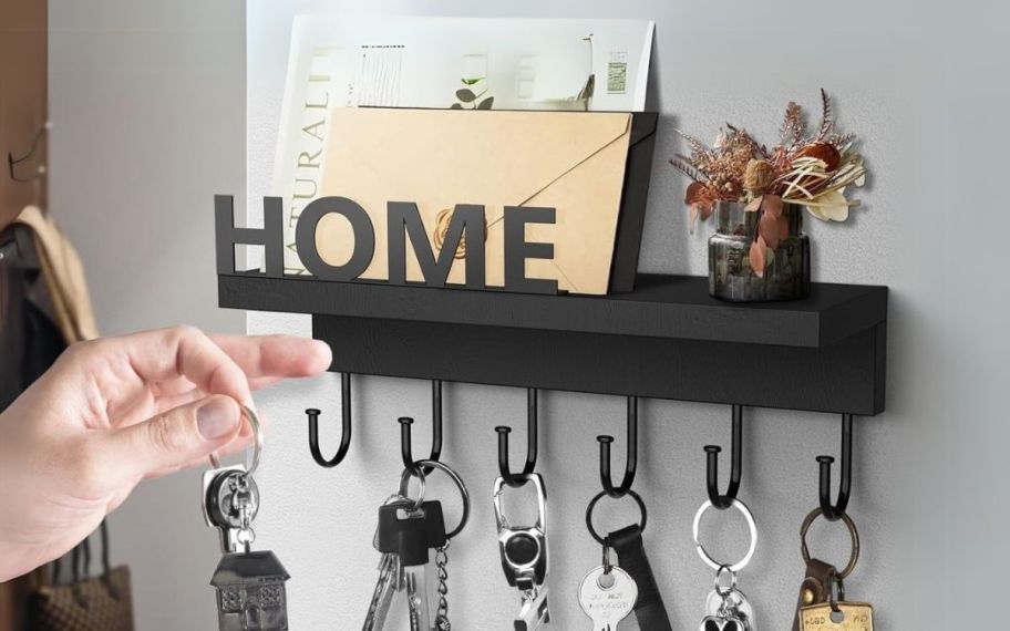 a mans hand placing a set of keys on a key hook. 