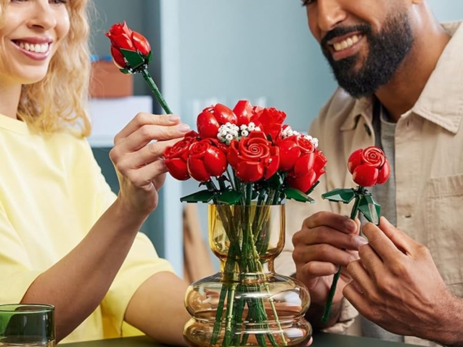 woman and man putting red LEGO roses into a vase