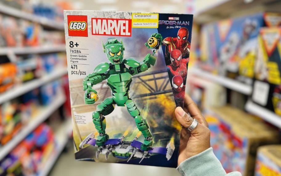 a womans hand holding a LEGO marvel green gobblin building toy